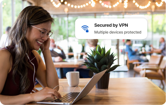 Woman at a cafe laughing at a laptop screen